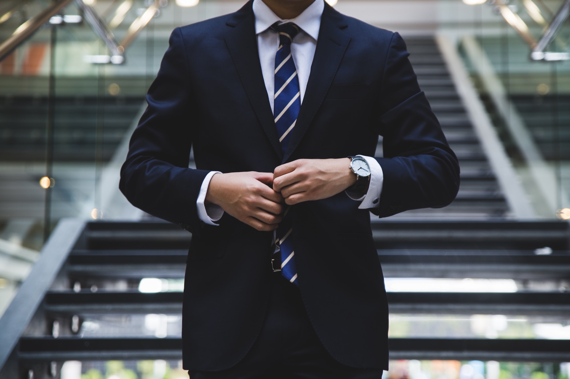 businessman walking down stairs while buttoning his jacket